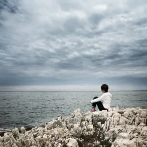 lonely woman sitting stormy sea toned desaturated photo copy space solitude concept 50597759